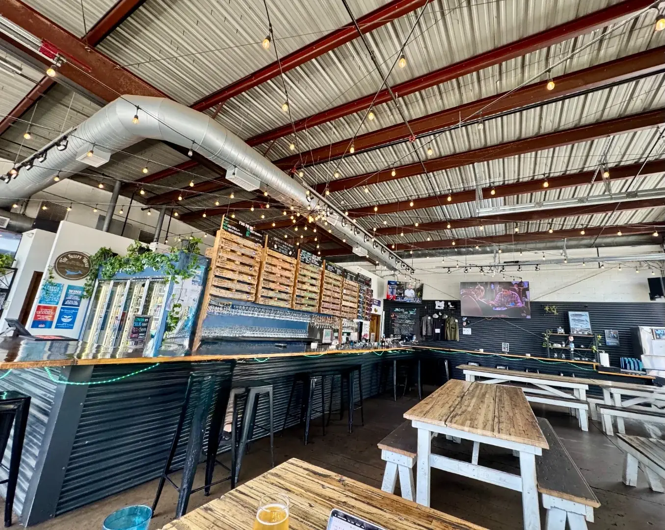 The Sleepy Whale taproom interior with a long bar and string lights