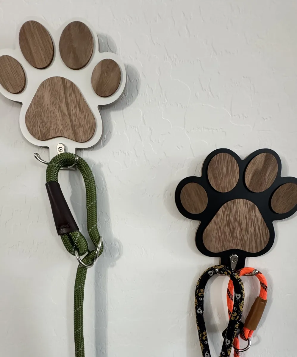 Two paw-print leash hooks on a white wall, holding three rope leashes